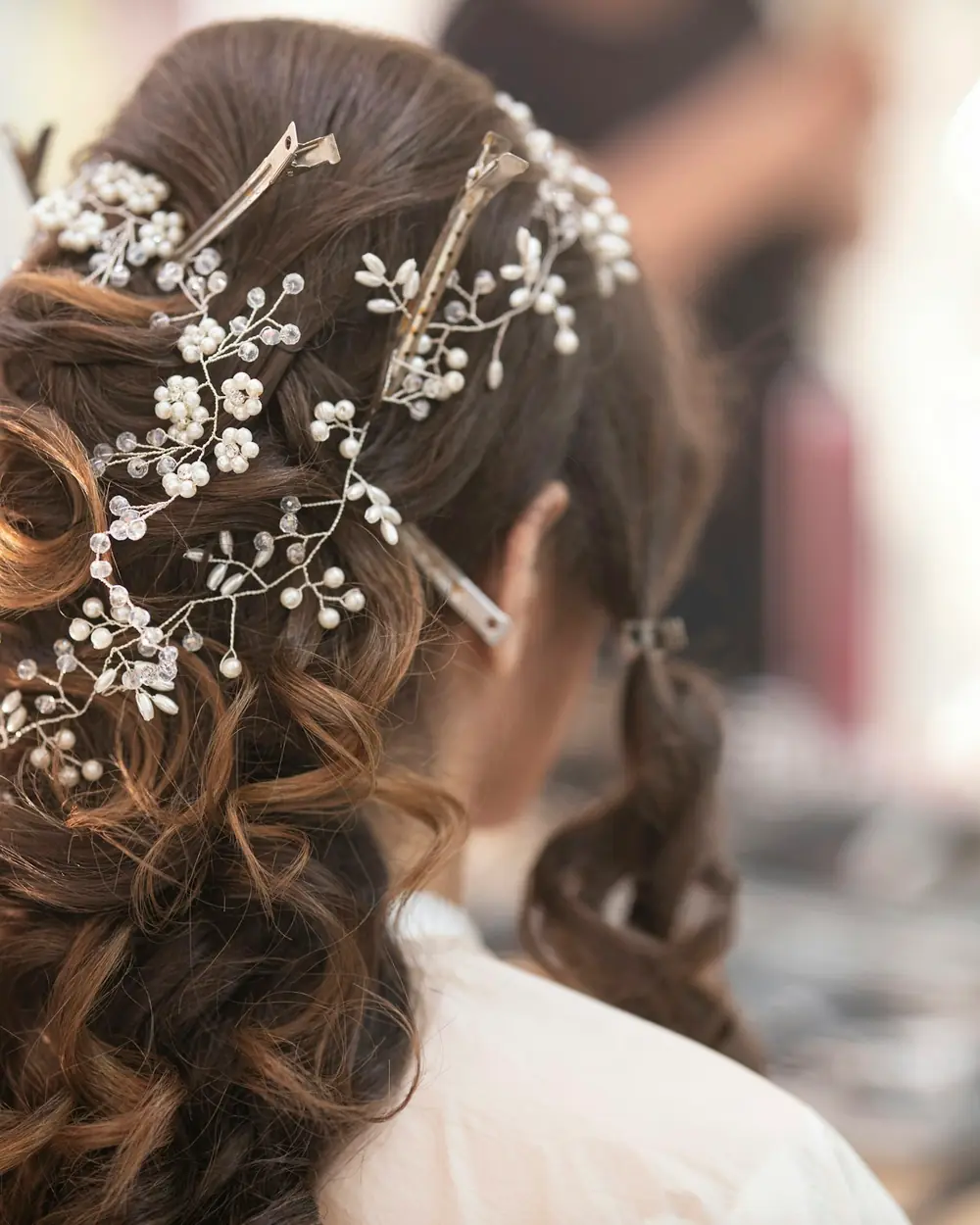 A bridal half-up style with a pearl and crystal hair vine