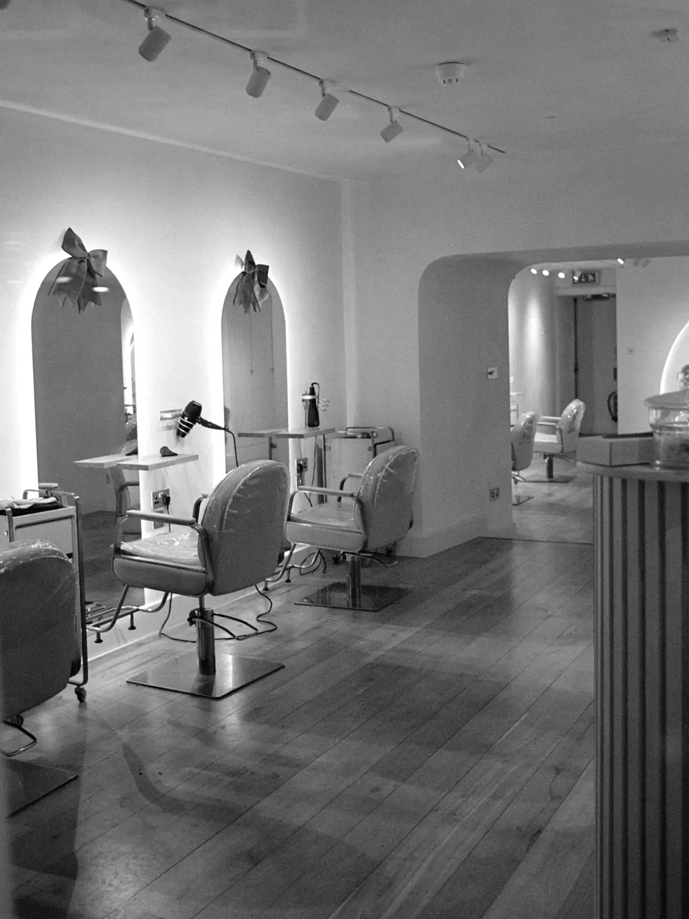 The salon floor: arched mirrors, grey chairs and pale timber